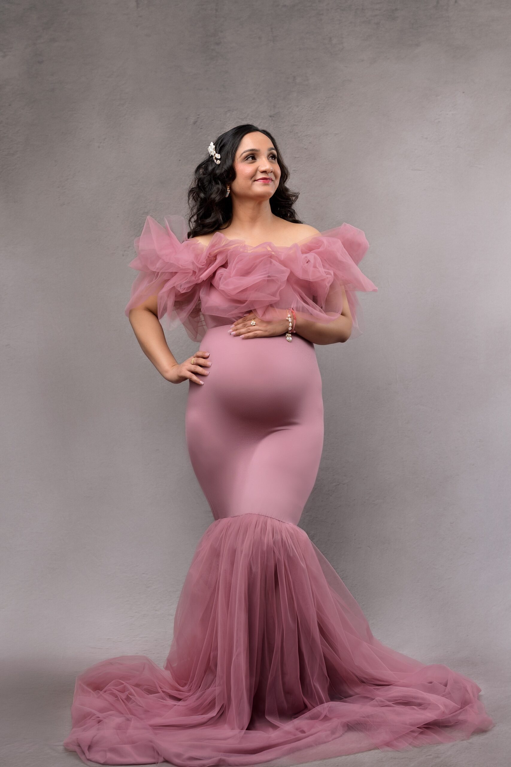 Pregnant woman in glamorous mermaid style pink gown, photographed at a Kansas City maternity studio.