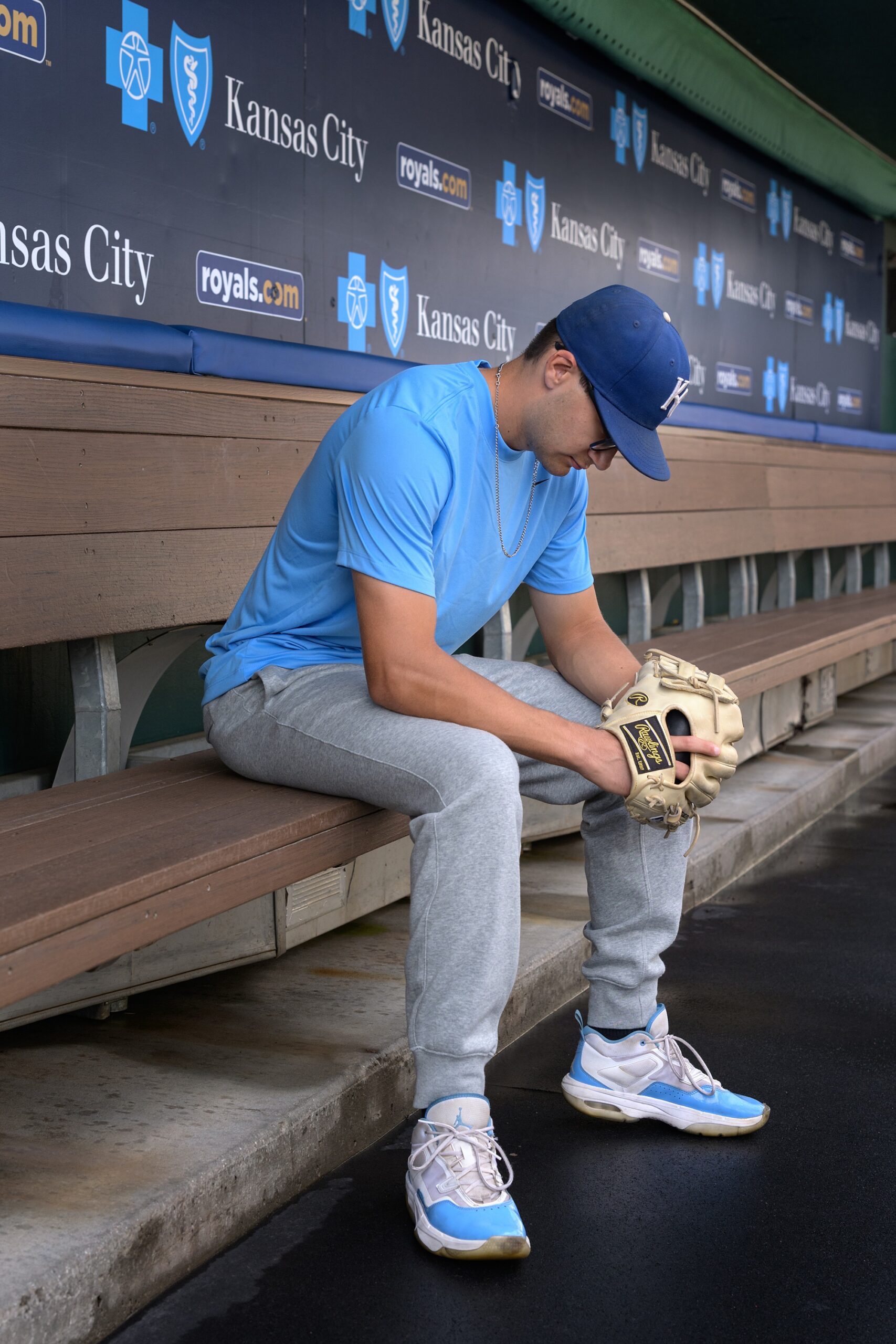 Senior sitting in the baseball dugout of a MLB stadium for his senior pictures by Helen Ransom Photography.