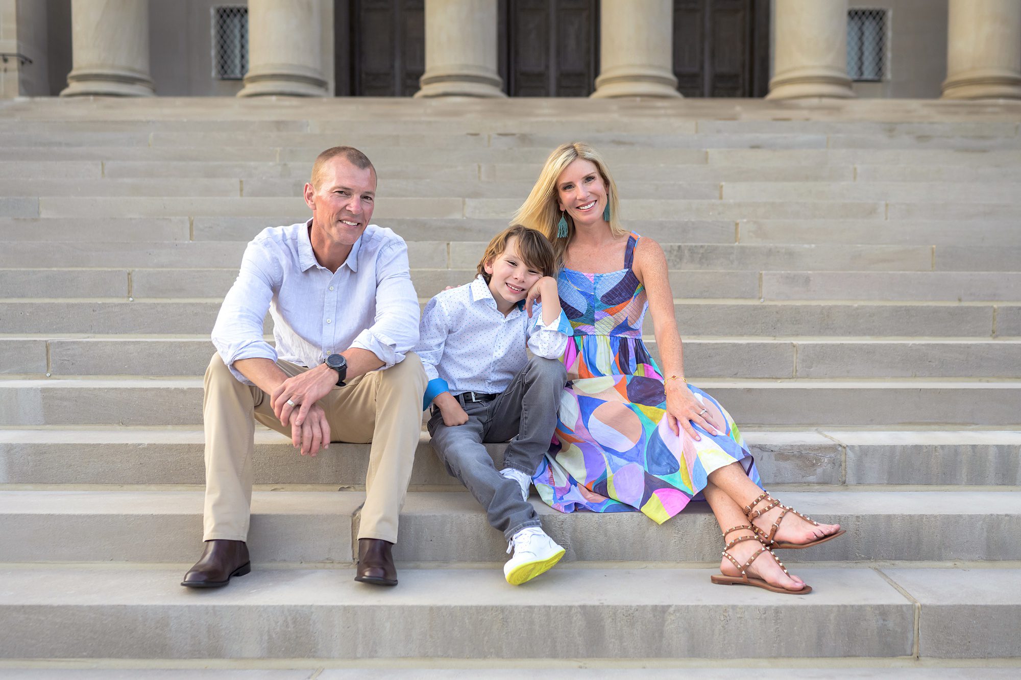 Family of three sitting on the steps at the Nelson Atkins Museum of Art in Kansas City, as photographed by Helen Ransom.