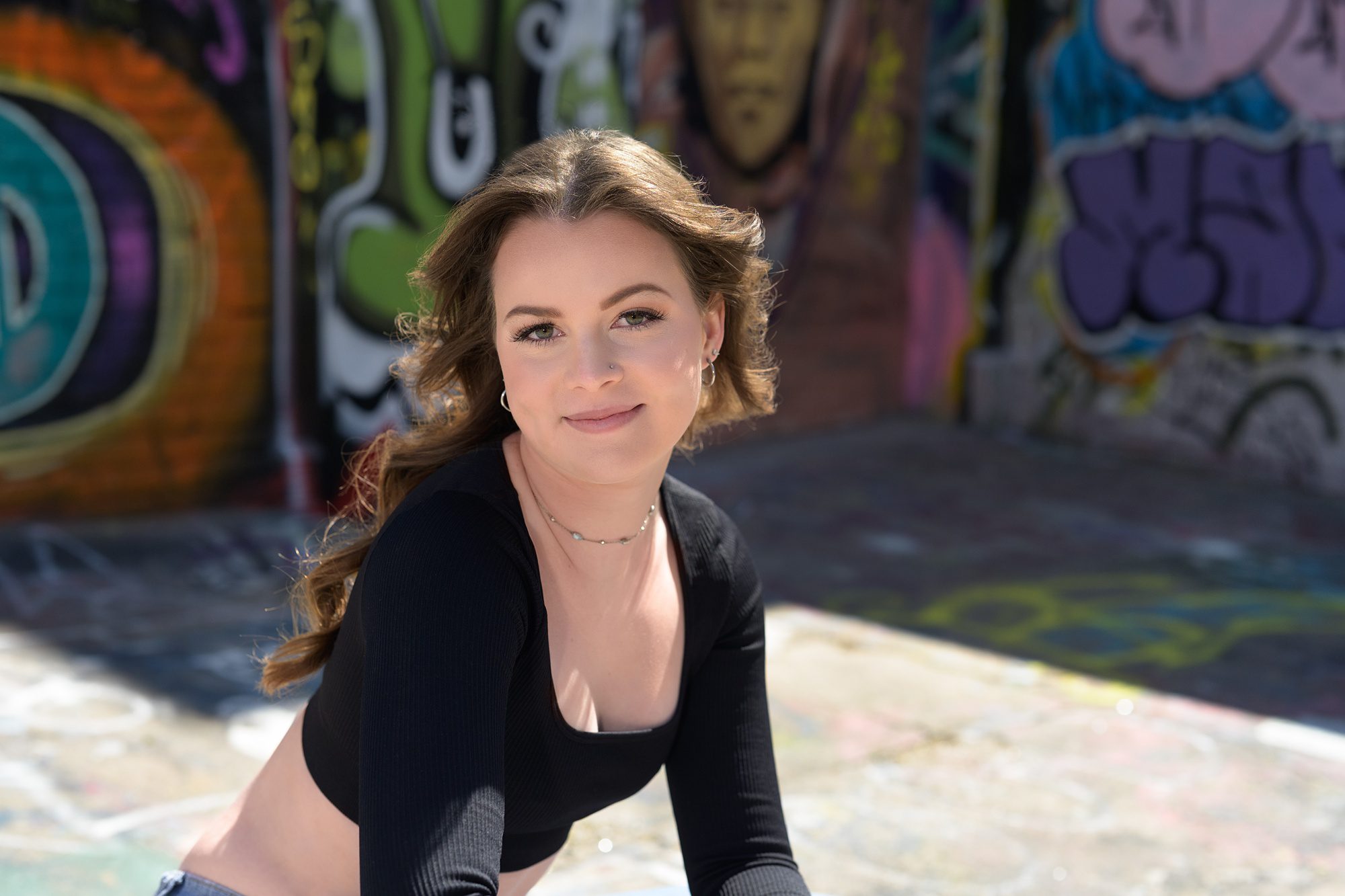 Senior pic of a girl in a black crop top in a brightly color graffiti alley in Kansas City.