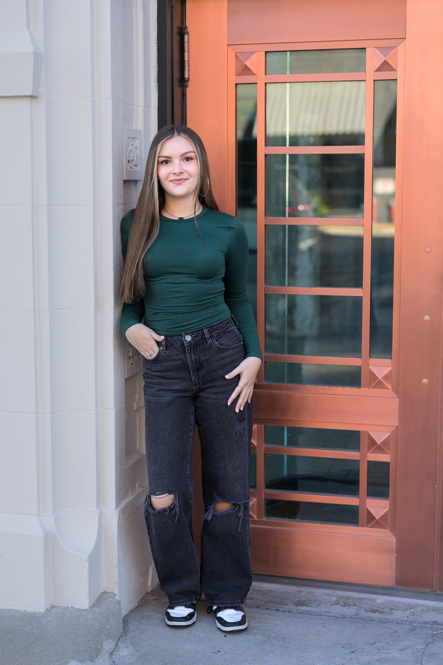 Senior girl from Lee's Summit posing in front of brass door in the Crossroads of Kansas City, at her senior photo session.