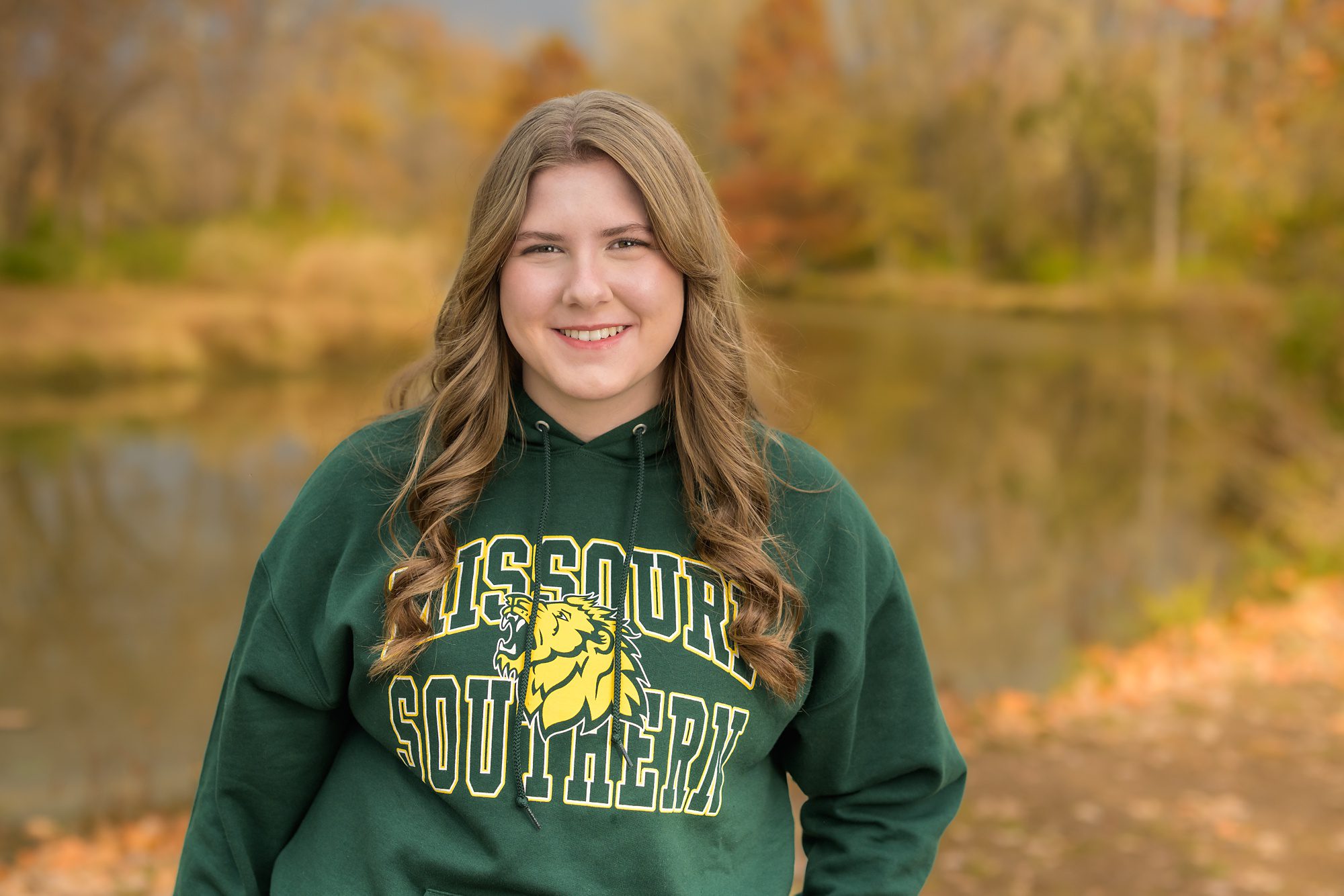 High School senior girl at her senior picture session, wearing the sweatshirt showing off where she plans to attend college.