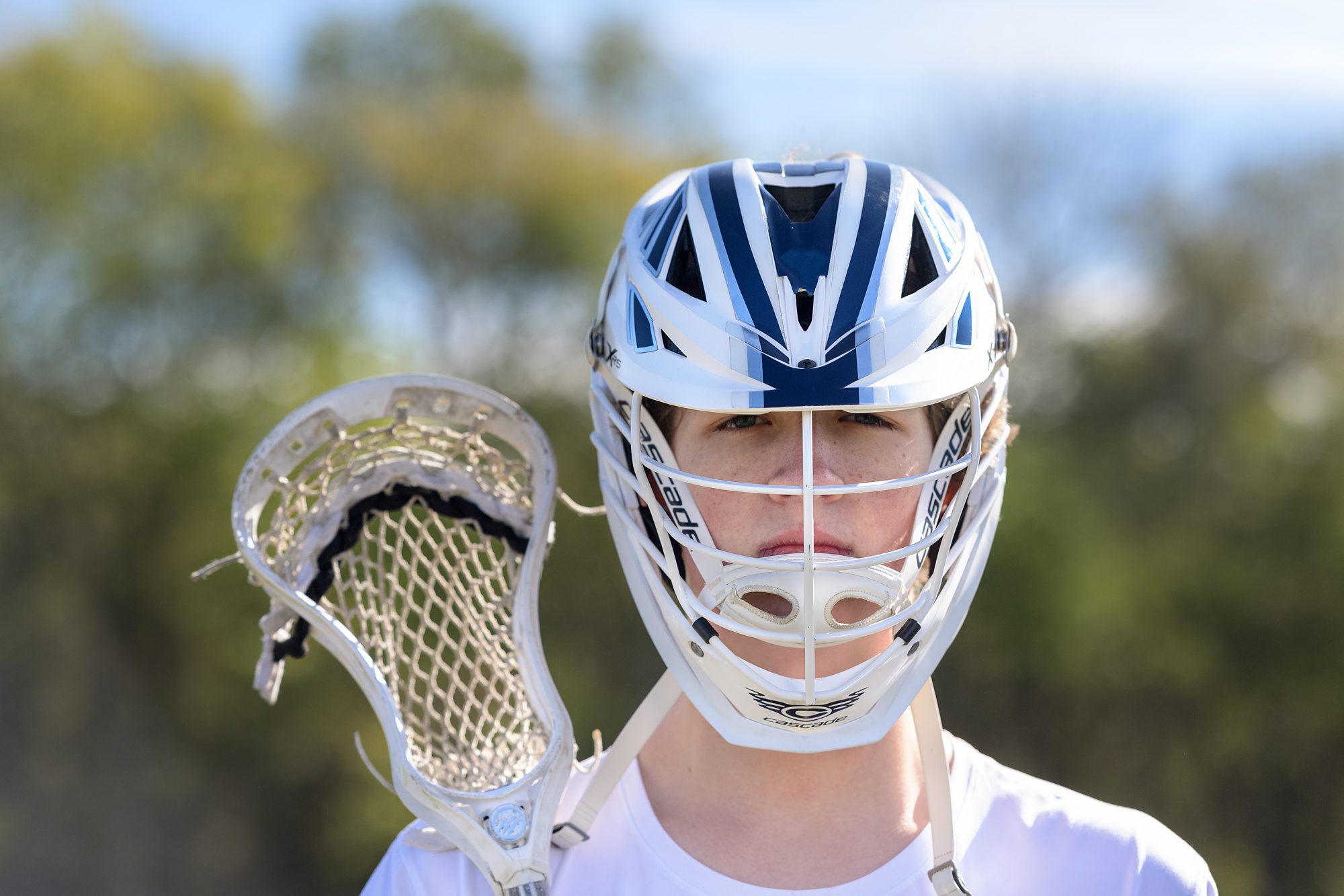 High school senior boy from Lawrence posing with his lacrosse mask and stick.